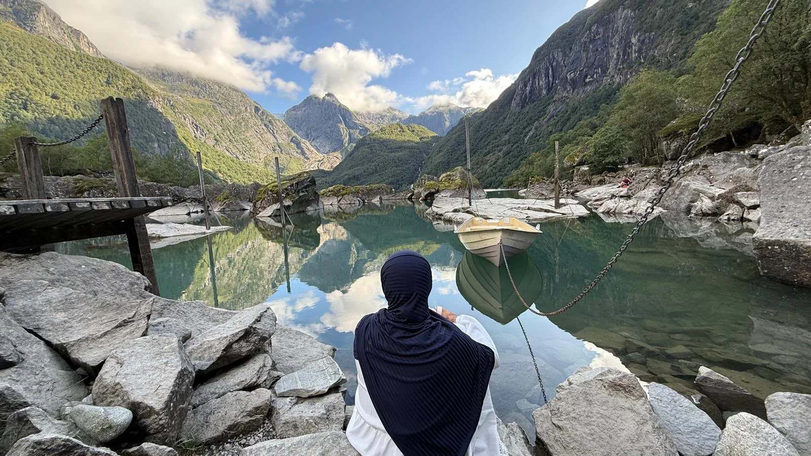 A still mountain lake with a moored boat, reflecting the sky